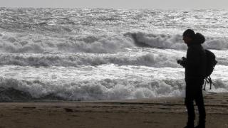 Una persona en la playa de la Malagueta visualizando el temporal en una imagen de archivo.