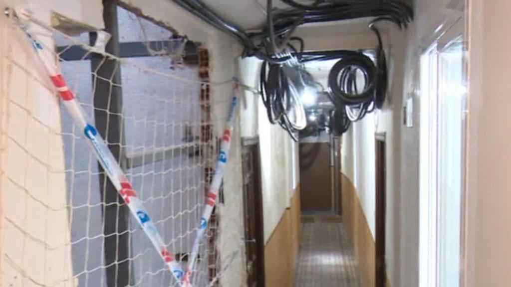 Pasillos del edificio en construcción con cableado sin terminar y agujeros en la pared.