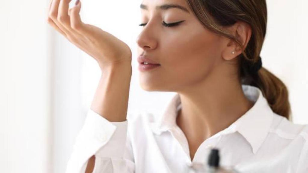 Mujer oliendo su propio perfume.