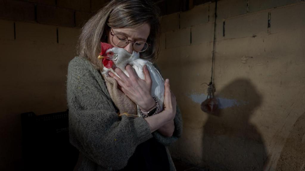 Una voluntaria del santuario 'Salvando Peludos' abrazando a una gallina de la granja.