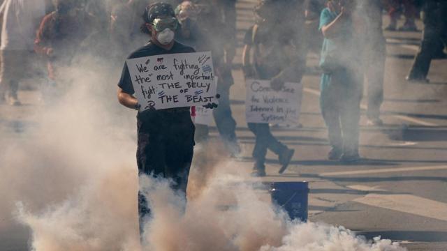 Un manifestante sostiene un cartel en medio de gases lacrimógenos mientras la gente protesta contra las políticas del presidente estadounidense Donald Trump y las redadas federales de inmigración durante una manifestación del Día del No a los Reyes Magos en Los Ángeles, California, EEUU, el 14 de junio de 2025.