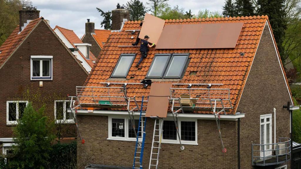 Una persona instalando las placas solares de terracota en una casa.
