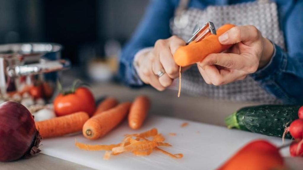 Imagen de una mujer pelando una zanahoria.