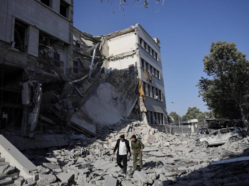 Hombres caminan entre los escombros, después de potentes ataques aéreos sacudieron Damasco el miércoles, dirigido al Ministerio de Defensa, como Israel prometió destruir las fuerzas del gobierno sirio que atacan a las comunidades drusas en el sur de Siria y exigió su retirada, en Damasco 16 de julio 2025.