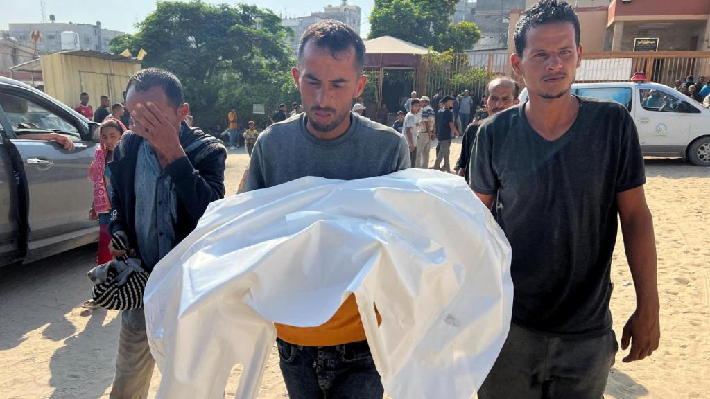Un hombre lleva el cuerpo de su hijo tras los ataques de Israel este viernes en Gaza.