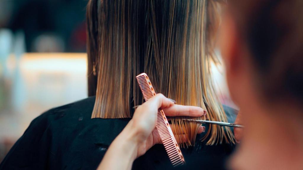 Un peluquero corta el cabello a un clienta