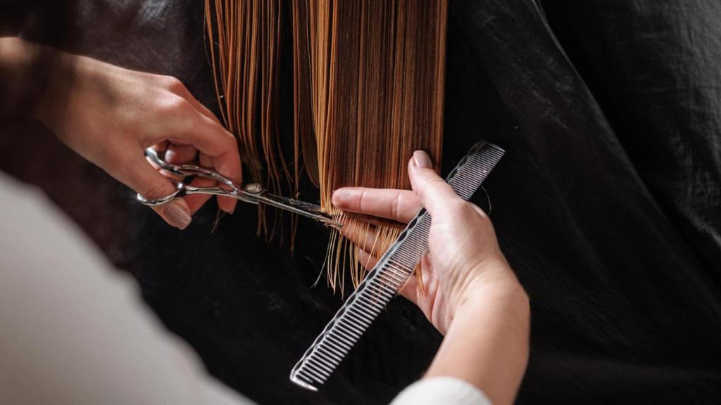 Un peluquero le hace un corte de pelo a una mujer