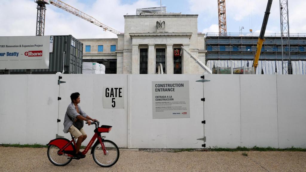 Una persona en bicicleta pasa por delante de las obras de la sede de la Fed.