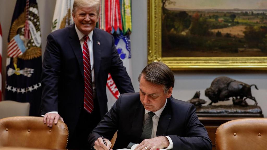 El presidente estadounidense Donald Trump junto al expresidente brasileño Jair Bolsonaro firma en el libro de visitas de la Casa Blanca