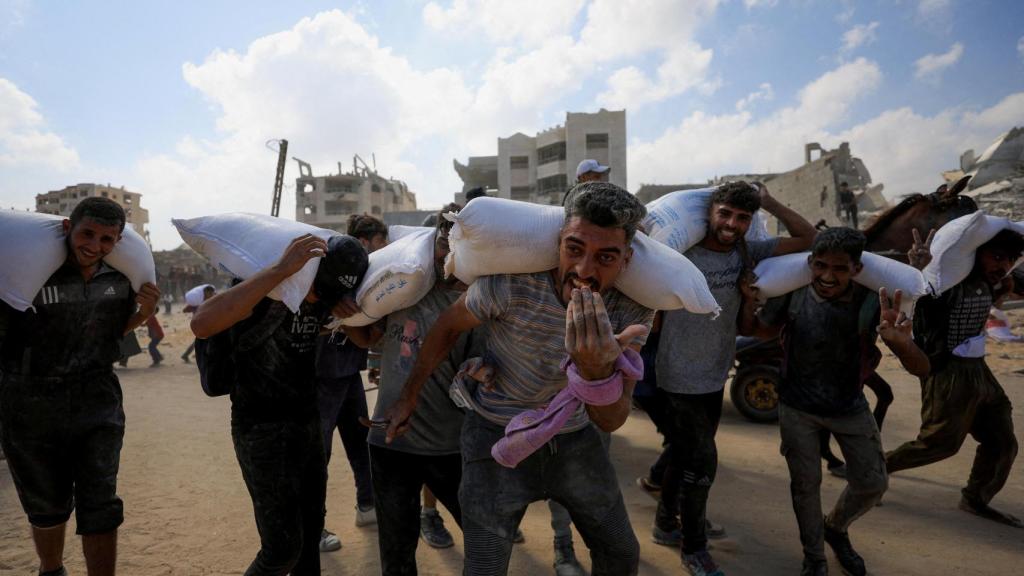 Palestinos transportan ayuda humanitaria que entró en Gaza a través de Israel.