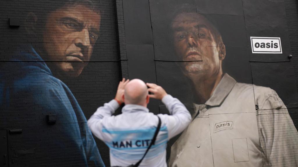 Un hombre toma fotografías de un mural de Oasis antes de sus conciertos en Heaton Park en Mánchester. Foto: Reuters /Phil Noble