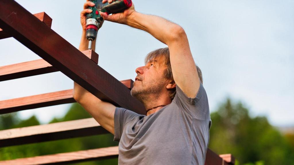 Un hombre montando una pérgola.