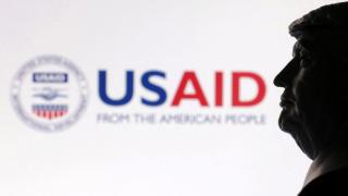 Una impresión 3D del presidente Donald Trump fotografiada junto al logo de USAID.