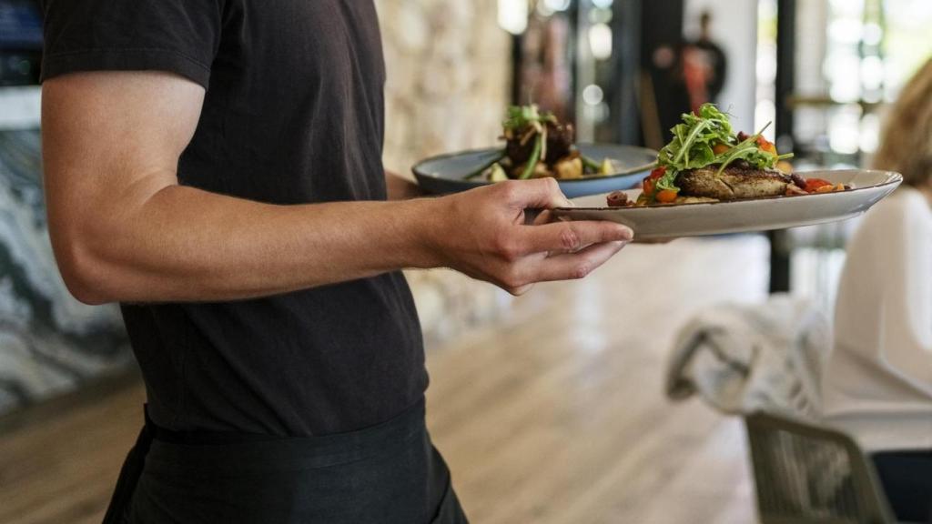 Camarero sirve comida en un restaurante.