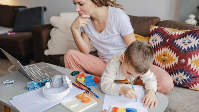Imagen de archivo de una madre teletrabajando con su hijo.