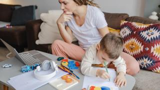Imagen de archivo de una madre teletrabajando con su hijo.