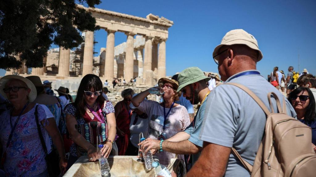Turistas se refrescan mientras visitan la Acrópolis durante la ola de calor de principios de julio.