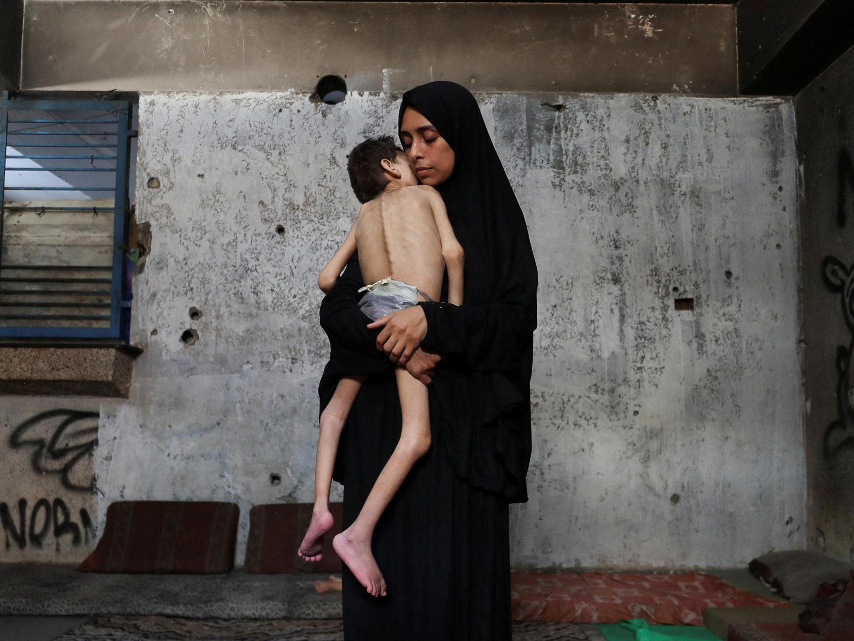 Una madre desplazada sostiene a su hijo en la ciudad de Gaza.