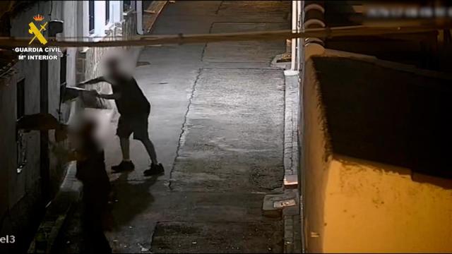 Los dos detenidos lanzando objetos contra la vivienda de las personas vulnerables.
