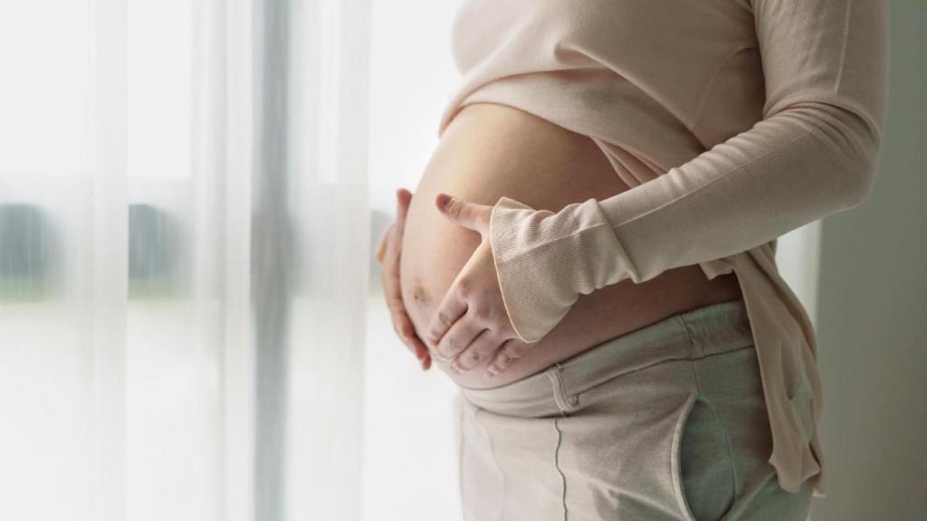 Una mujer embarazada sostiene las manos sobre el vientre