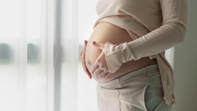 Una mujer embarazada sostiene las manos sobre el vientre