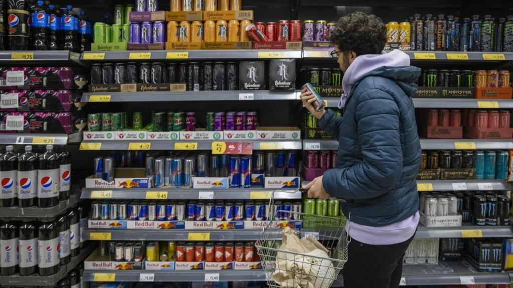 Un joven observa el pasillo de las bebidas energéticas de un supermercado.