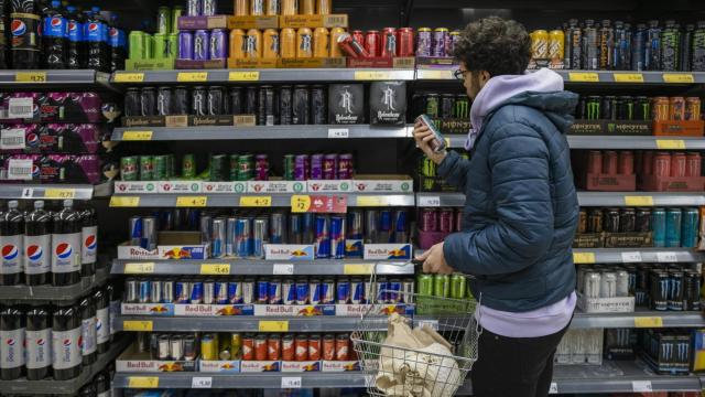 Un joven observa el pasillo de las bebidas energéticas de un supermercado.
