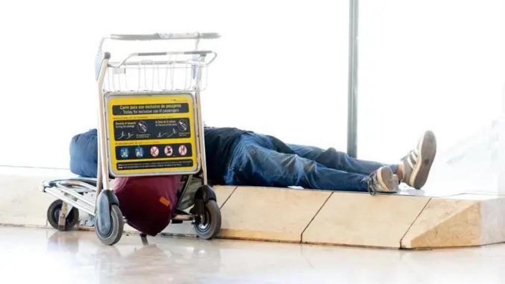 Una persona durmiendo en Barajas.