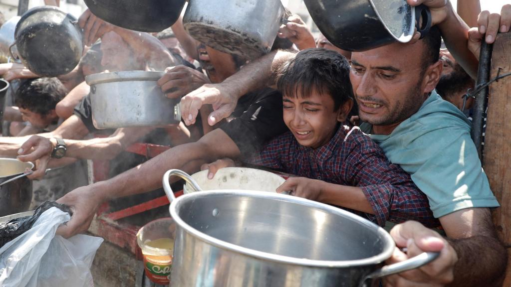 Palestinos acuden a las colas del hambre para recoger comida.