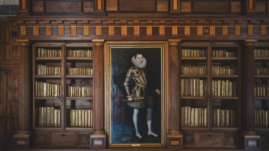 Estanterías del salón principal de la Real Biblioteca del Monasterio de El Escorial, con un cuadro de Felipe II.