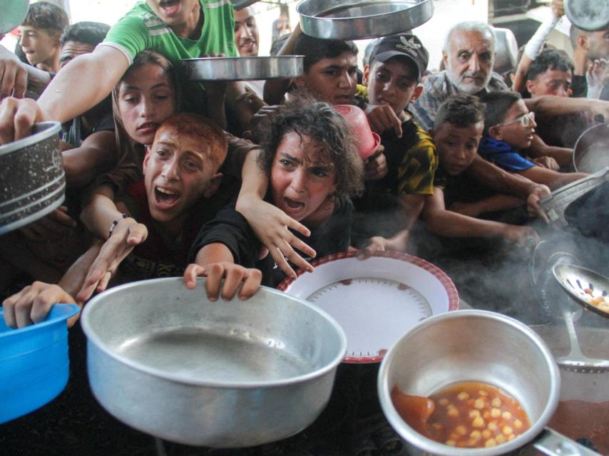 Palestinos acuden a las colas del hambre para recoger comida.