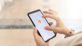 Mujer de la mano con un smartphone buscando en un mapa de la ciudad restaurantes.