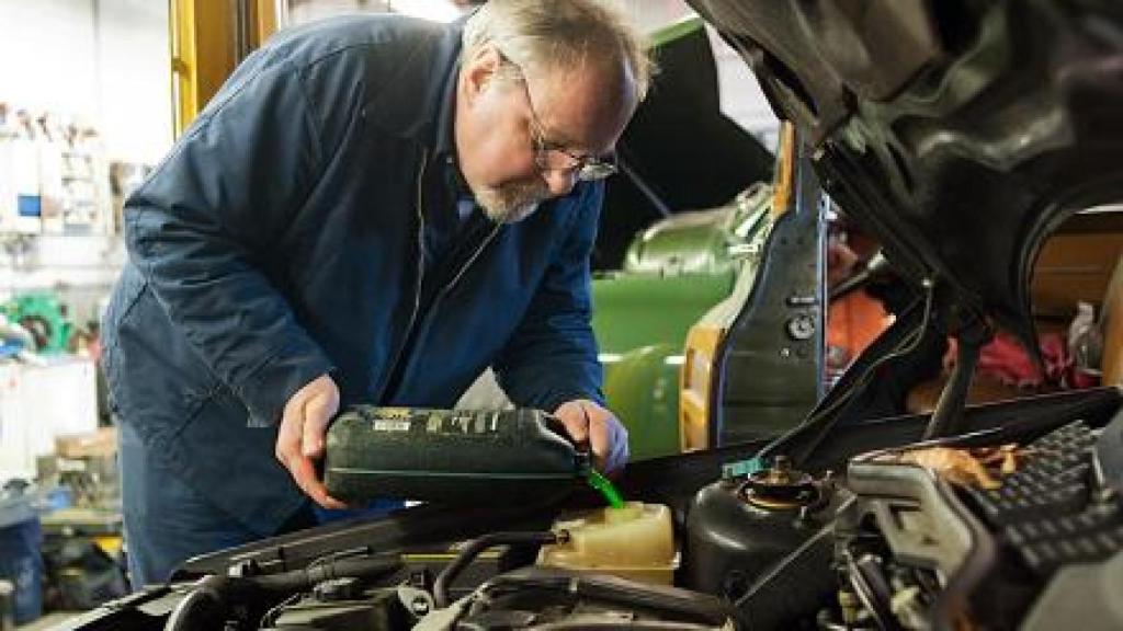 Imagen de un mecánico rellenando el líquido refrigerante.