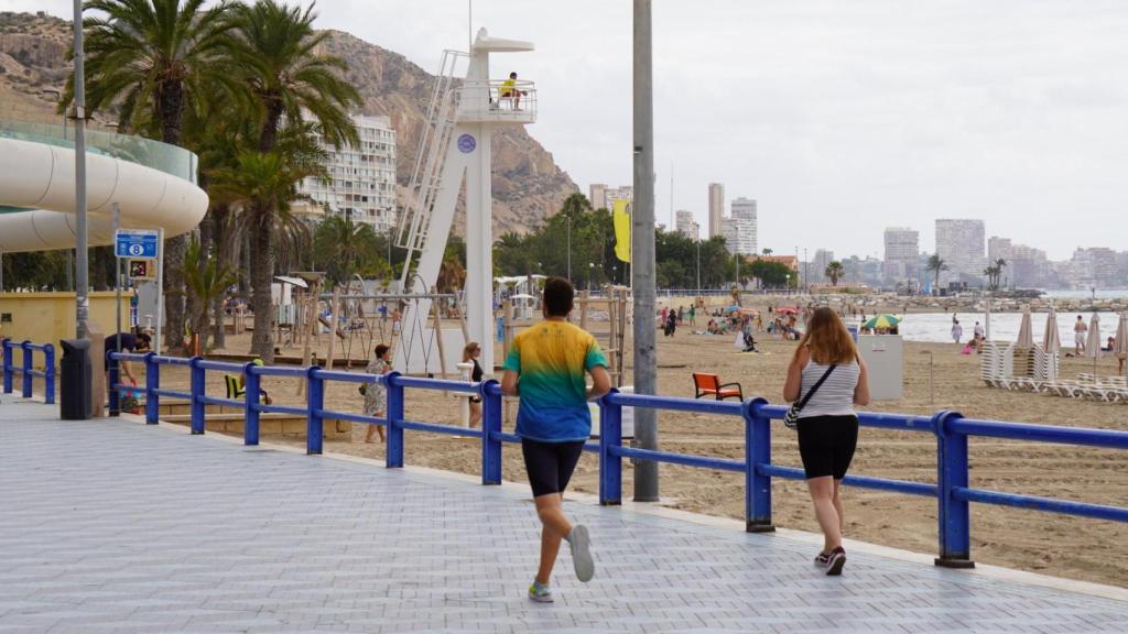 Deportistas y bañistas en la playa del Postiguet.