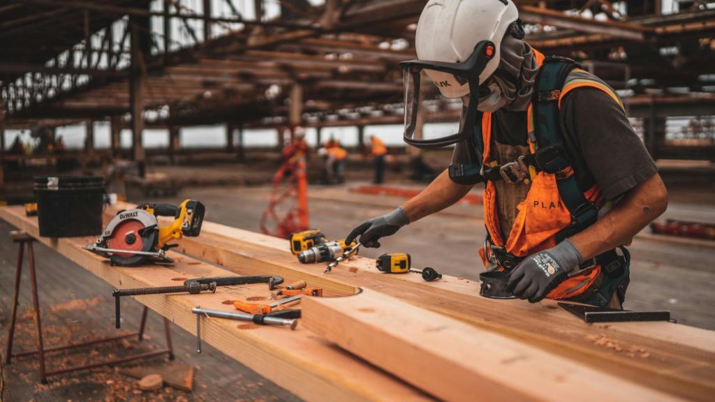 Un trabajador de una obra con una madera.