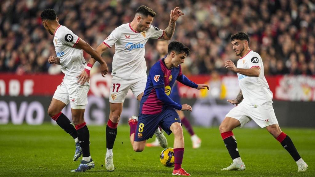 Pedri trata de mantener el balón ante la presión de tres jugadores del Sevilla.