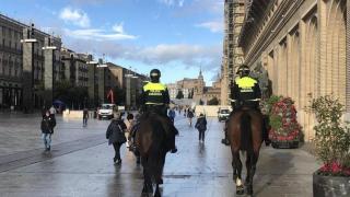 Dos agentes de la policía local montados sobre dos miembros del escuadrón, en la plaza del Pilar de Zaragoza.