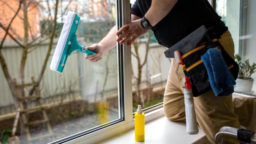 Un operario limpiando las ventanas de una vivienda