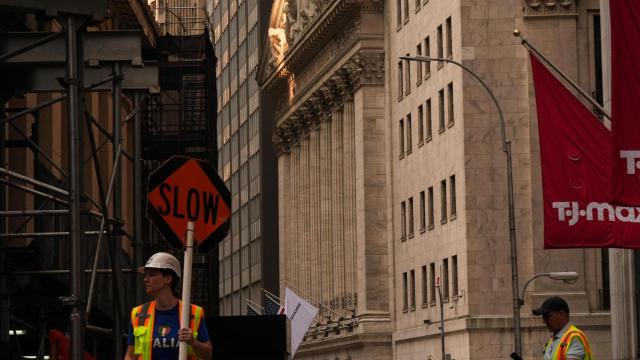 Un trabajador sostiene un cartel de Despacio frente a la Bolsa de Nueva York.