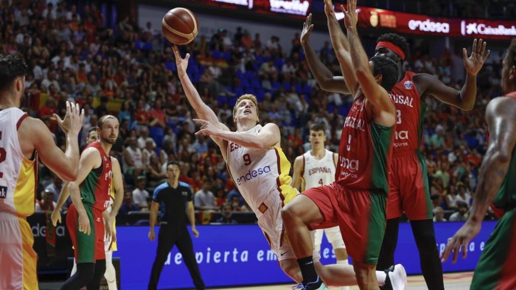Alberto Díaz penetra a canasta ante la oposición de la defensa lusa.
