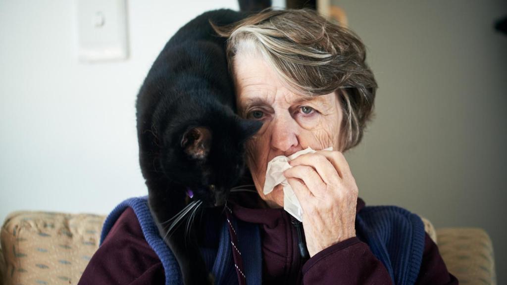 Una señora alérgica a los felinos, con un gato en la espalda.