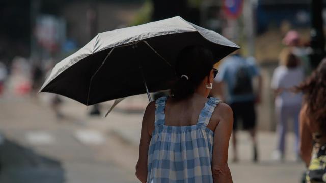 Una mujer se protege del sol con una sombrilla