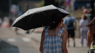Una mujer se protege del sol con una sombrilla