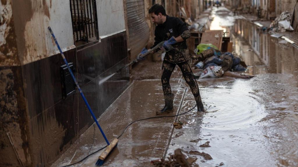 Varias personas limpian el barro acumulado por la dana en un municipio valenciano. Alejandro Martínez / EP