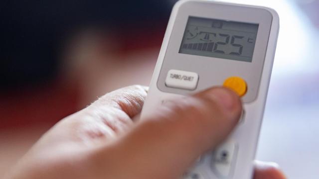 Imagen de archivo de una persona encendiendo un aire acondicionado.