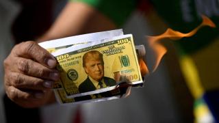 Un manifestante sostiene un billete de dólar falso en llamas con la cara del presidente estadounidense Donald Trump durante una protesta contra los aranceles a los productos brasileños.