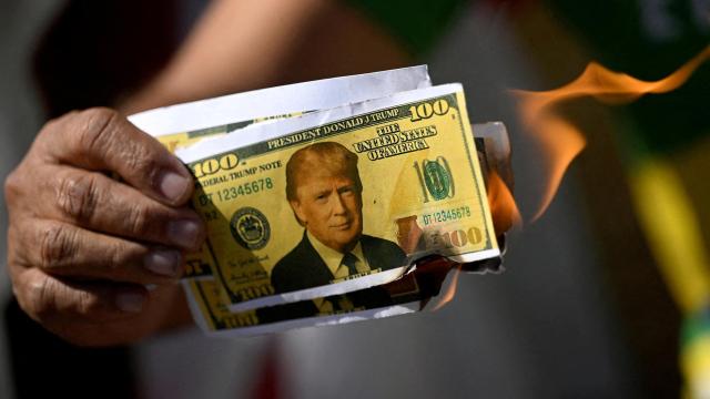 Un manifestante sostiene un billete de dólar falso en llamas con la cara del presidente estadounidense Donald Trump durante una protesta contra los aranceles a los productos brasileños.