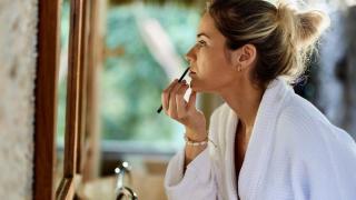 Mujer maquillándose los labios frente al espejo.