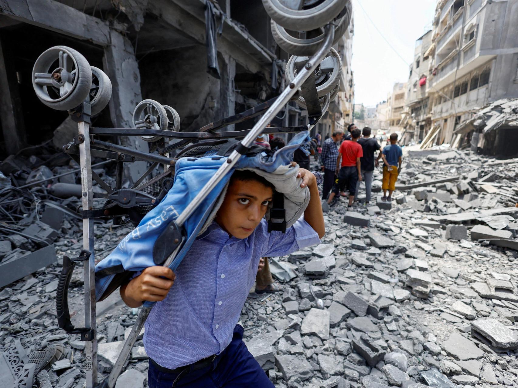 Un niño palestino lleva un cochecito en el lugar de un ataque israelí, el pasado viernes, contra Ciudad de Gaza.