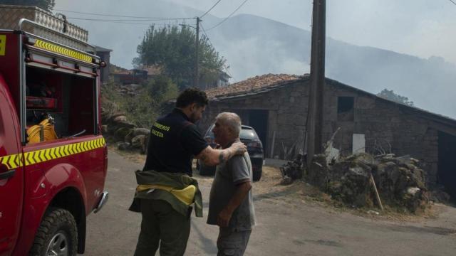 Un residente y un bombero después de la noche con el fuego alrededor de la aldea, a 10 de agosto de 2025, en Maceda, Ourense.